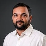 Professional portrait of a man in a white shirt against a gray background.